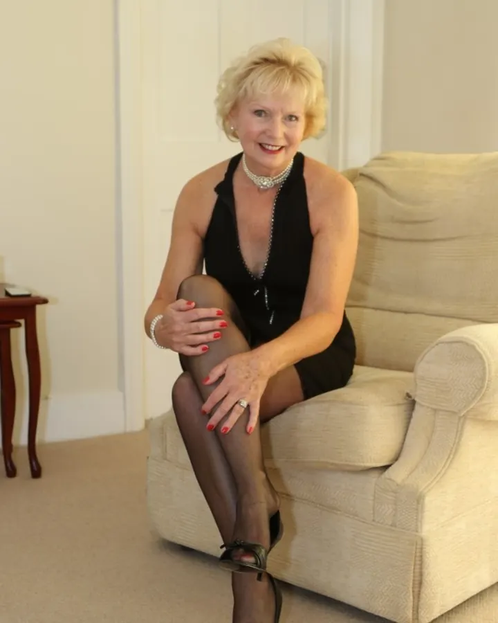 Femme blonde en robe rose posant sur un banc