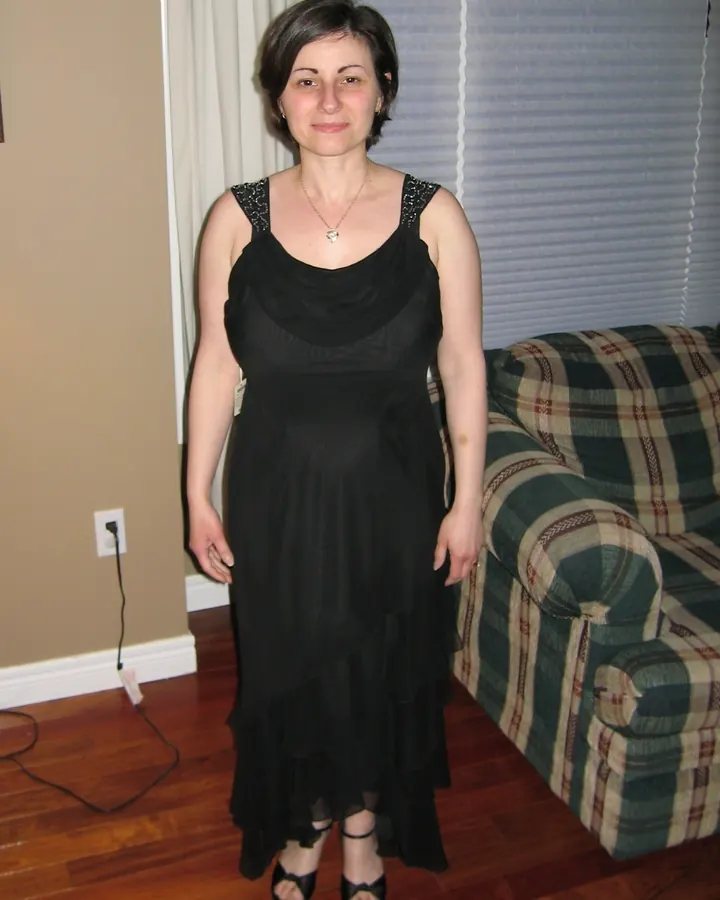 Femme en robe noire longue, debout dans un salon