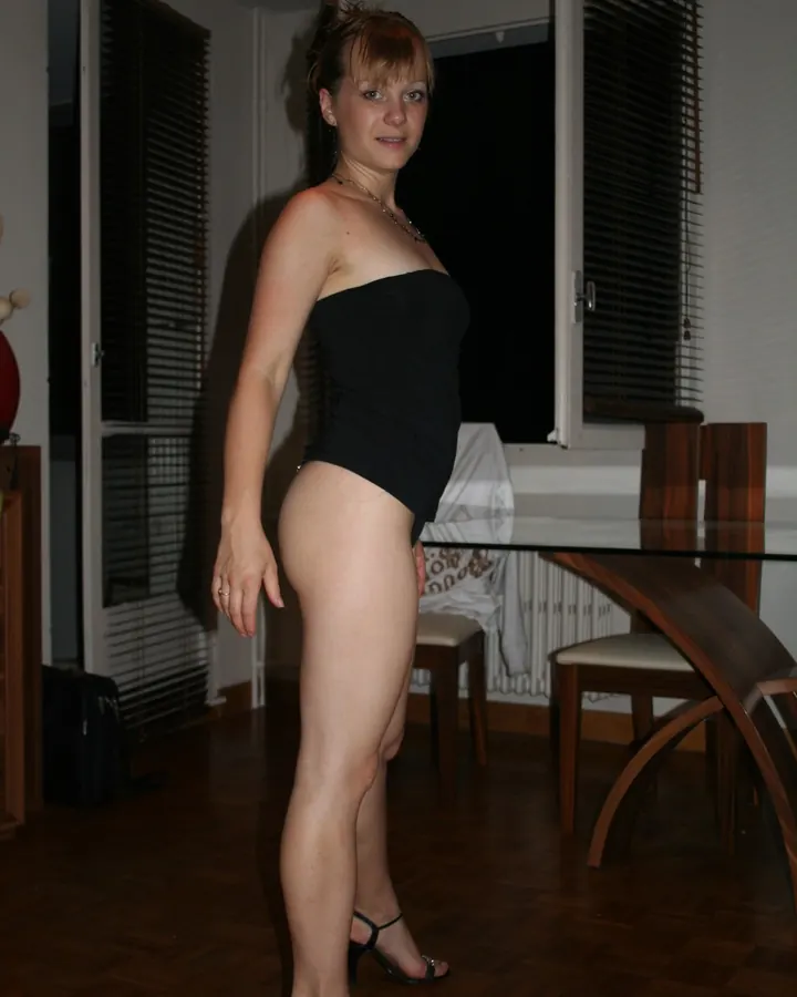 Femme en robe noire, debout dans une pièce, portant des sandales à talons hauts