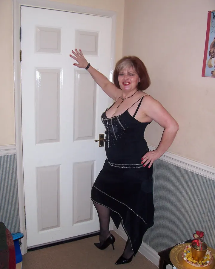 Femme en robe noire scintillante près d’une porte blanche