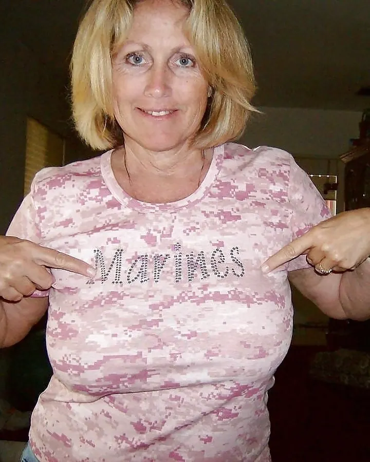 Femme souriante en t-shirt rose avec inscription 'Marines', pointant vers le texte.