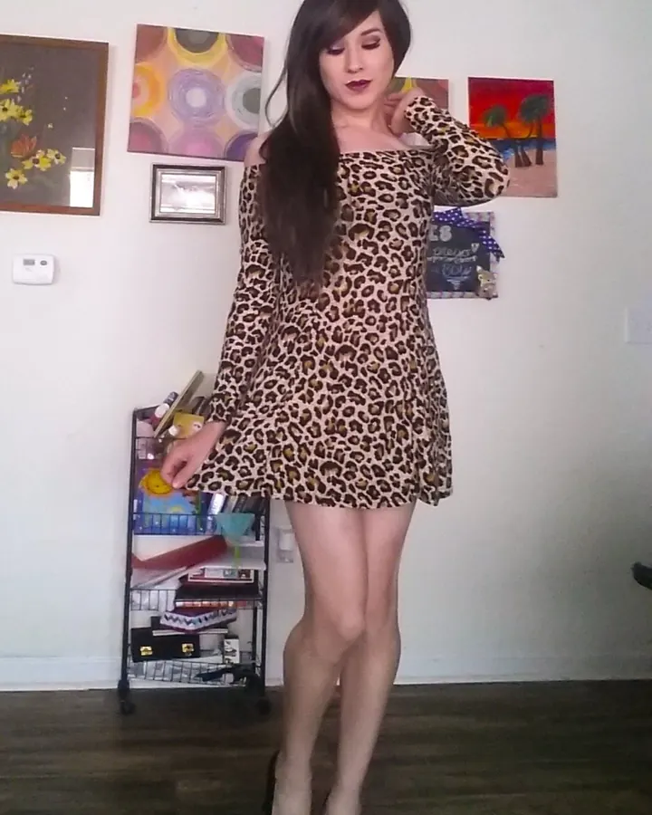Femme aux cheveux bruns, en bikini noir, prenant un selfie dans un miroir rond, dans une chambre moderne.